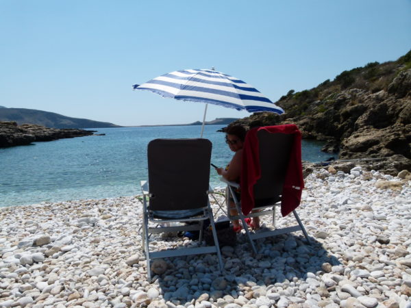 Jenny and our new beach umbrella overlooking a small bay with a pebble beach. 