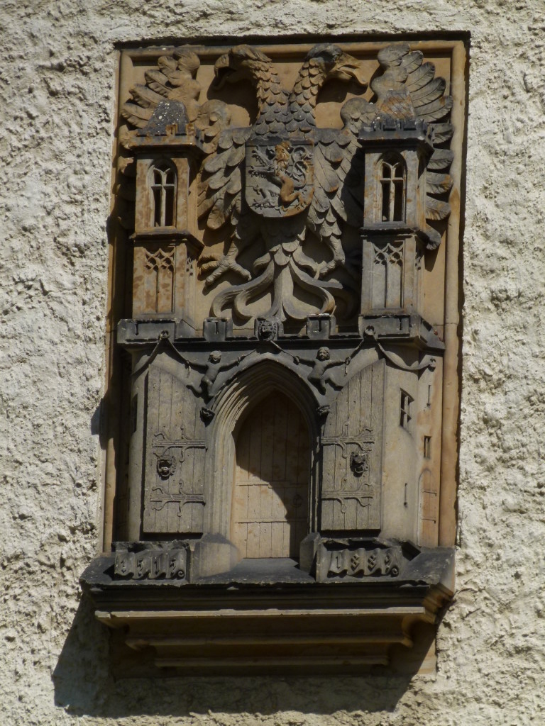 Wooden plaque on the outside wall above the gate