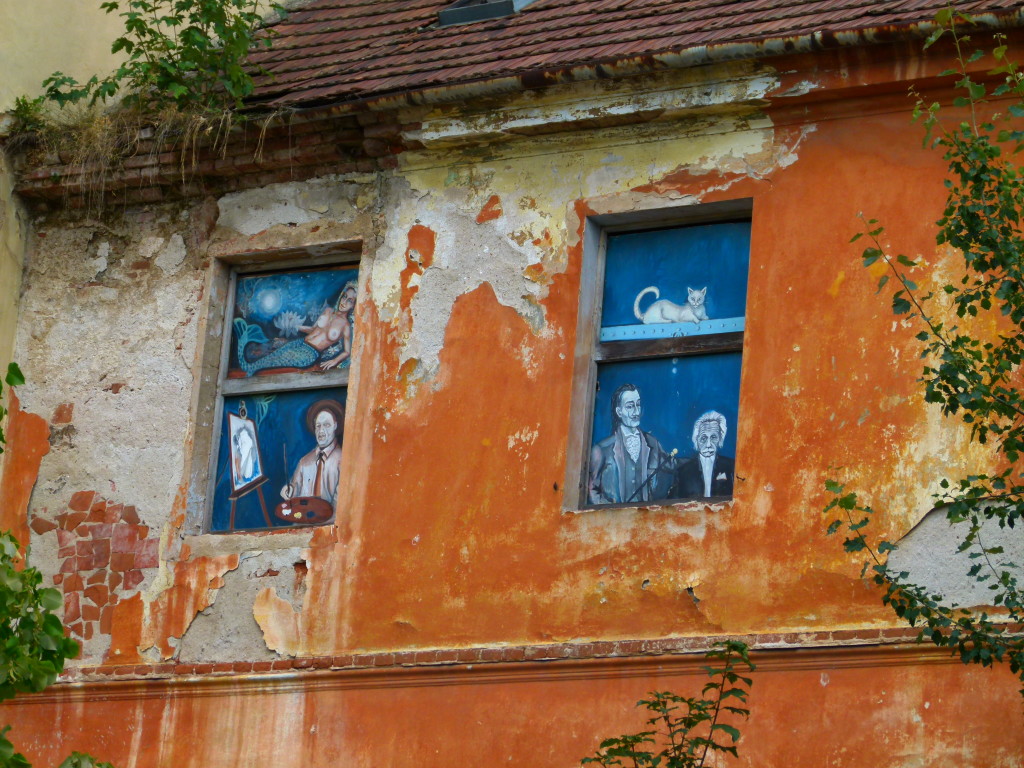 A derelict building with some artwork in the windows.