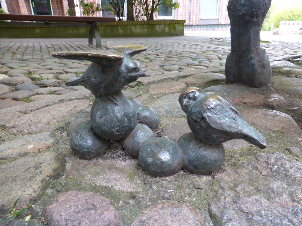 Birds are sitting on the house dung at the back of the statue.