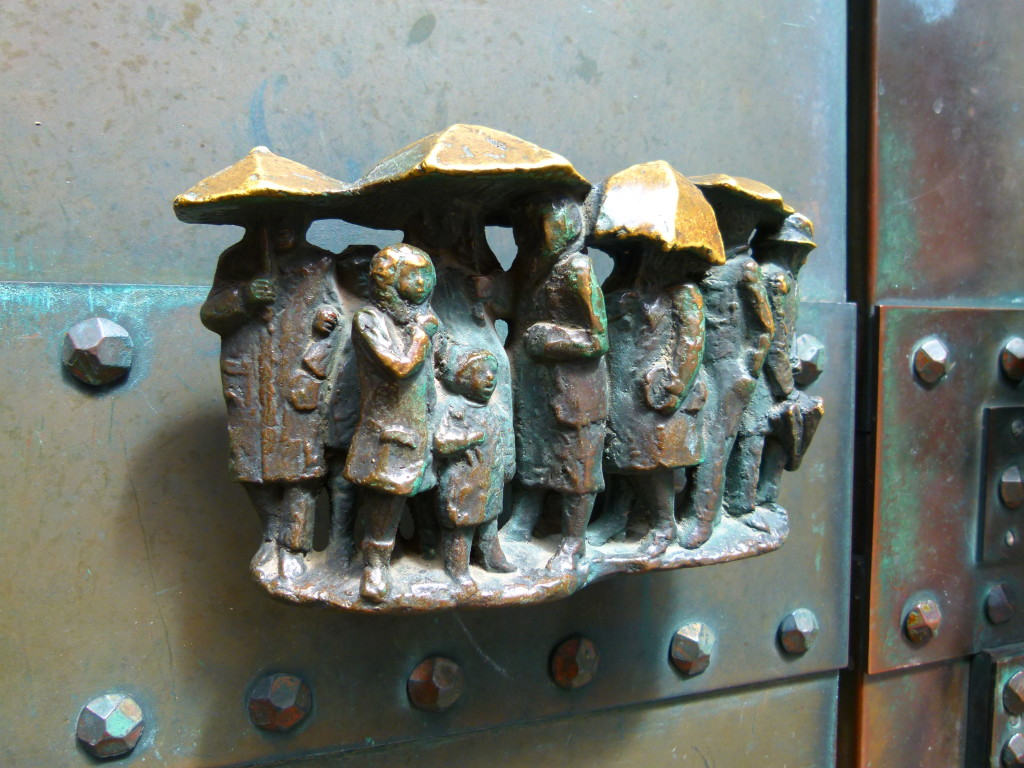 Door handle at the side of the church. Little people in the rain.